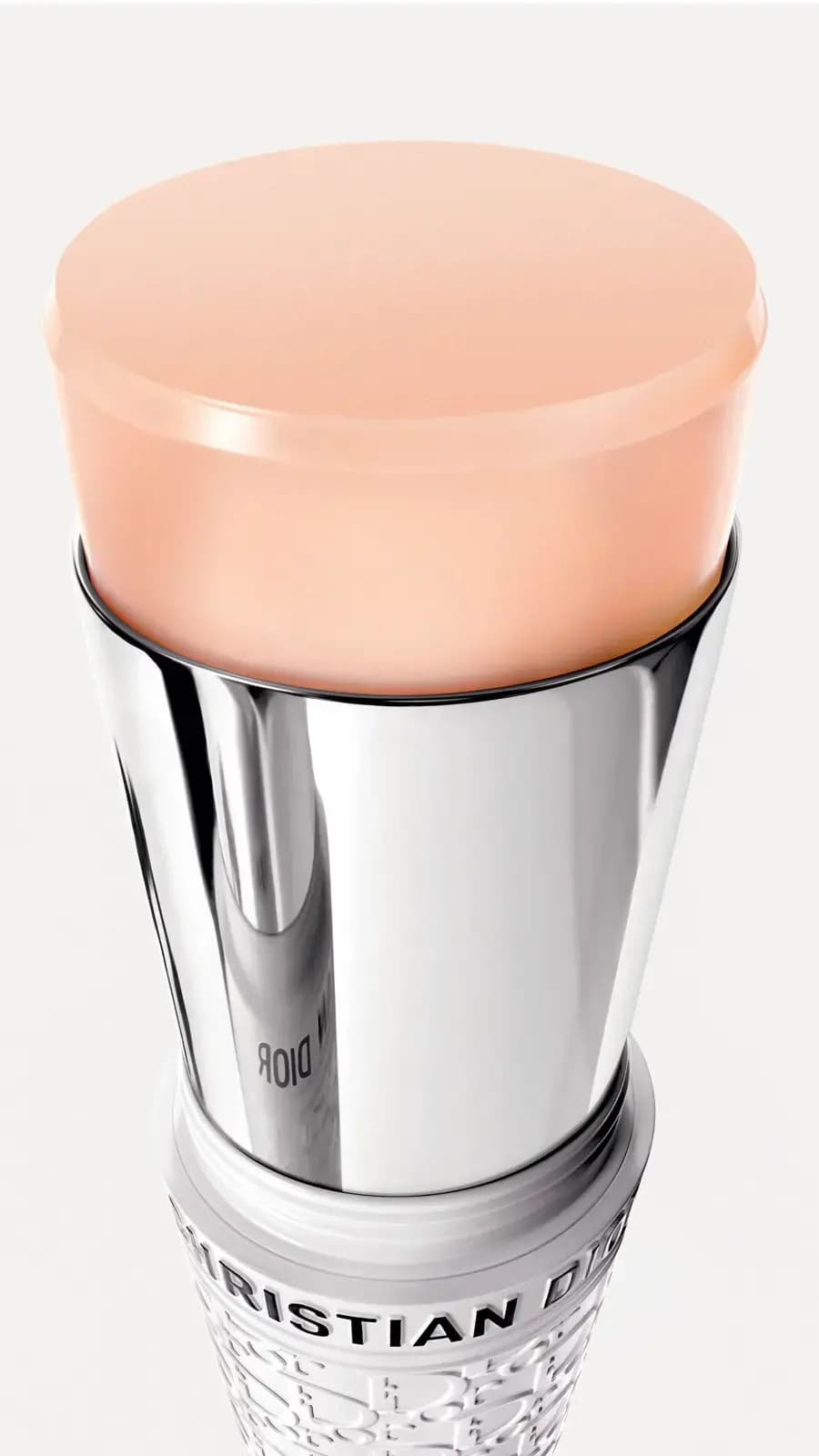 Close-up of the peach-toned stick bullet rising from a mirrored silver sleeve