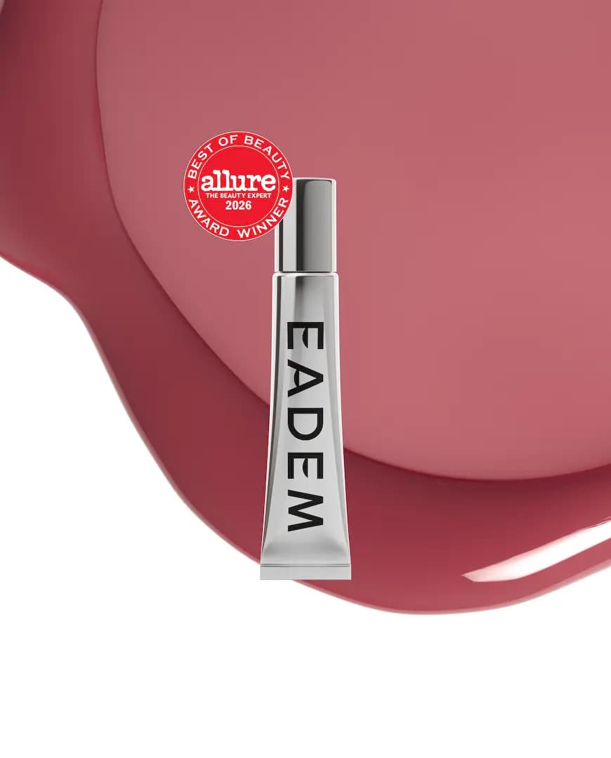 Silver EADEM tube with red Allure badge on a glossy deep mauve-rose balm pool