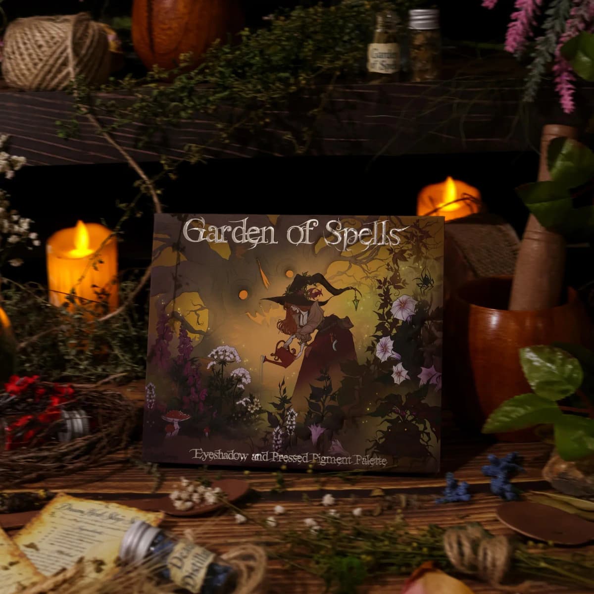 Garden of Spells Eyeshadow and Pressed Pigment Palette box with witch illustration among candles and dried herbs