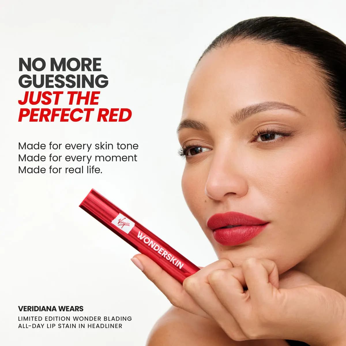 Model Veridiana with matte red lips rests her chin on her hand, holding the red Virgin Wonderskin tube