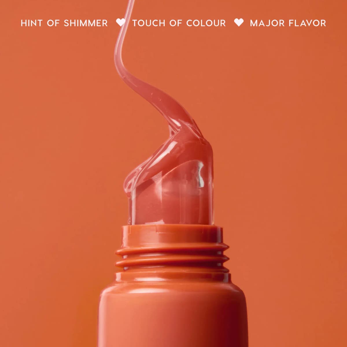 Ribbon of sheer peachy balm flowing from the tube tip on orange, captioned hint of shimmer, touch of colour, major flavor