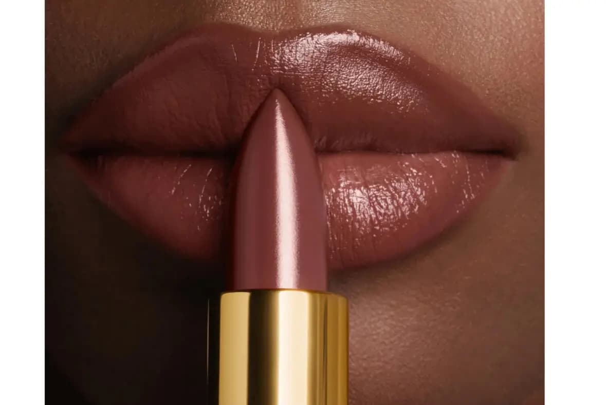 Glossy mauve-brown lips with a matching satin lipstick bullet in a gold tube held at center