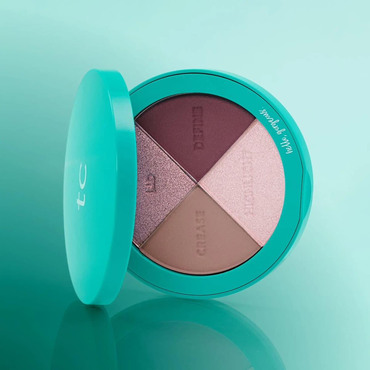 Signature Plums palette angled beside its teal lid on a reflective aqua surface, showing deep plum and pink pans.