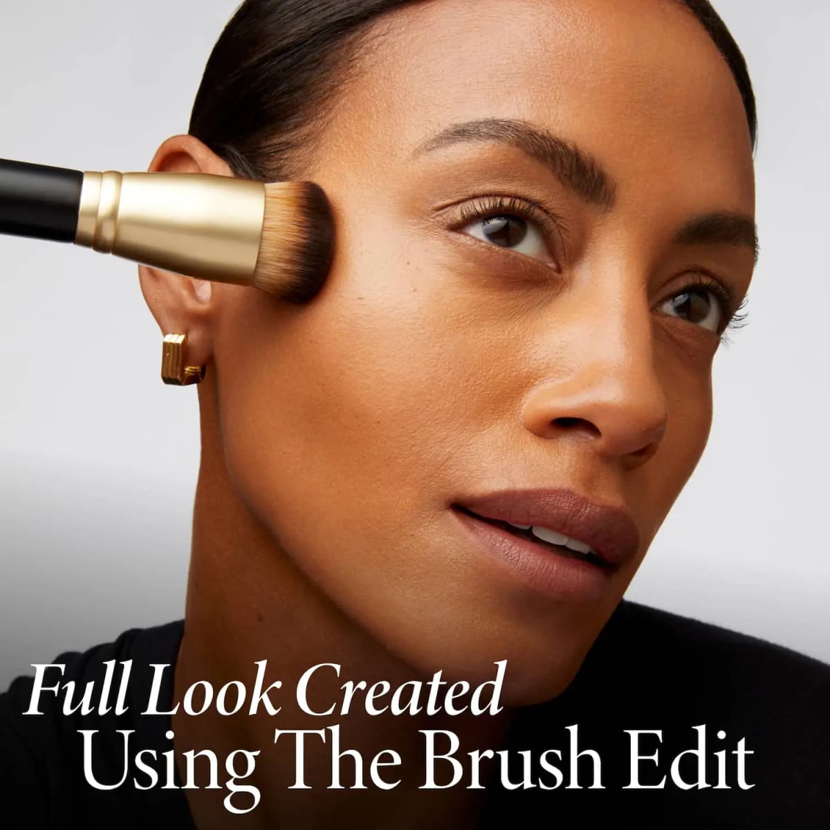 Model with sleek hair and gold earring as a flat-top gold-ferrule brush sweeps across the cheek; text says look made with set