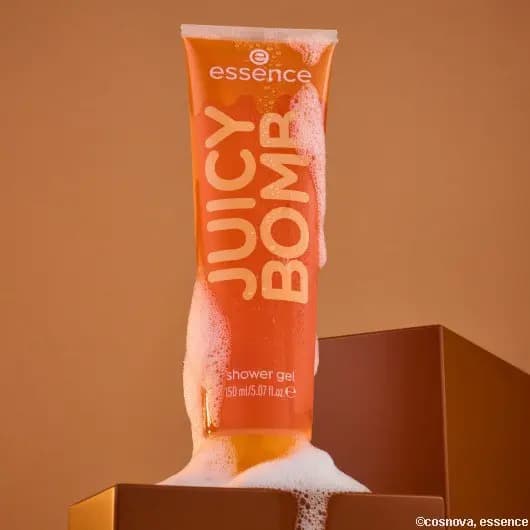 essence caramelted Juicy Bomb Shower Gel tube with foam on a brown block