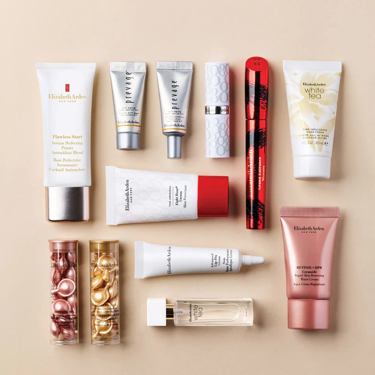 Flat lay of Elizabeth Arden minis on beige: Flawless Start, PREVAGE serums, ceramide capsules, Lip-Fix Cream and White Tea.