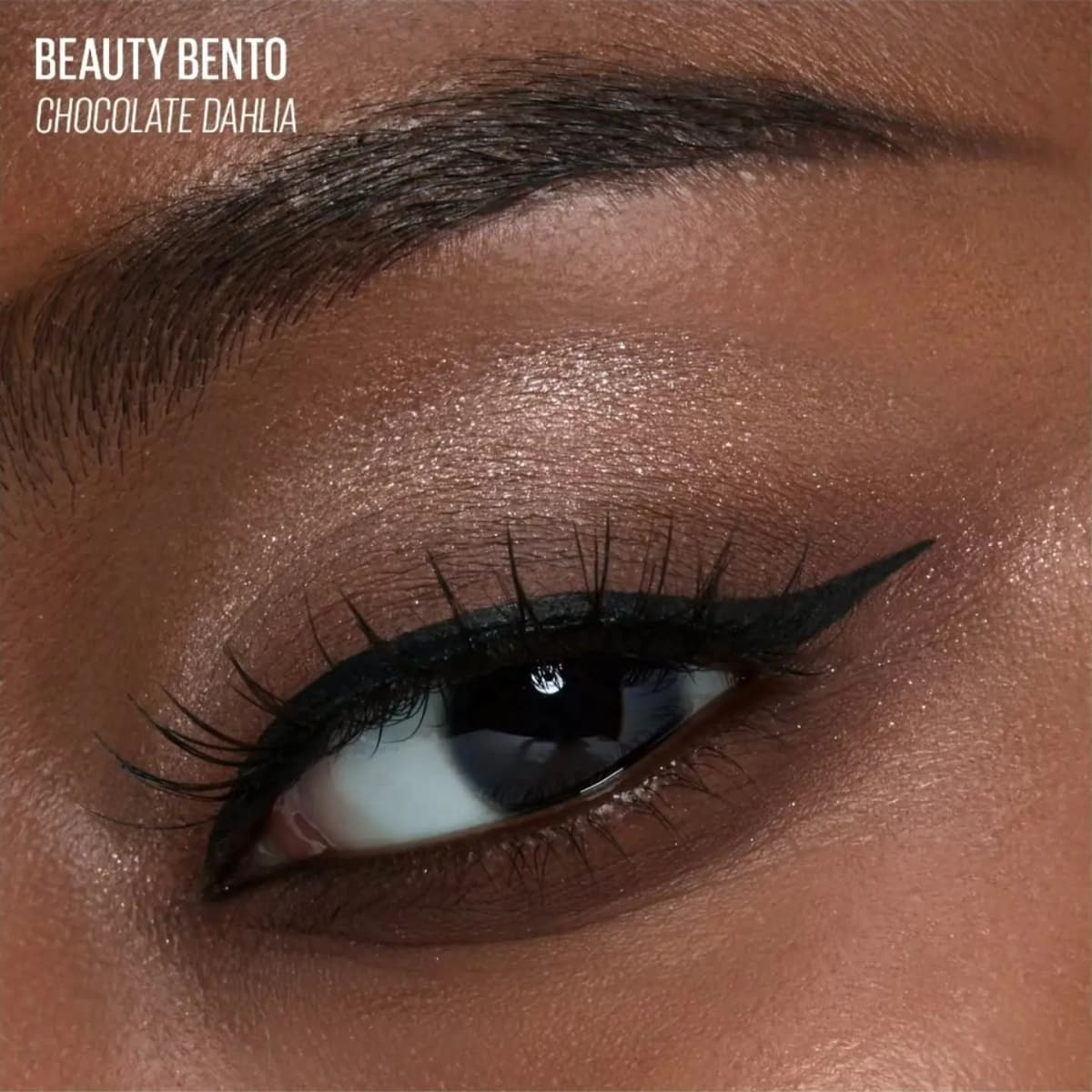 Close-up of a deep-skin eye wearing Beauty Bento Chocolate Dahlia shimmer on the lid with sharp black winged liner.