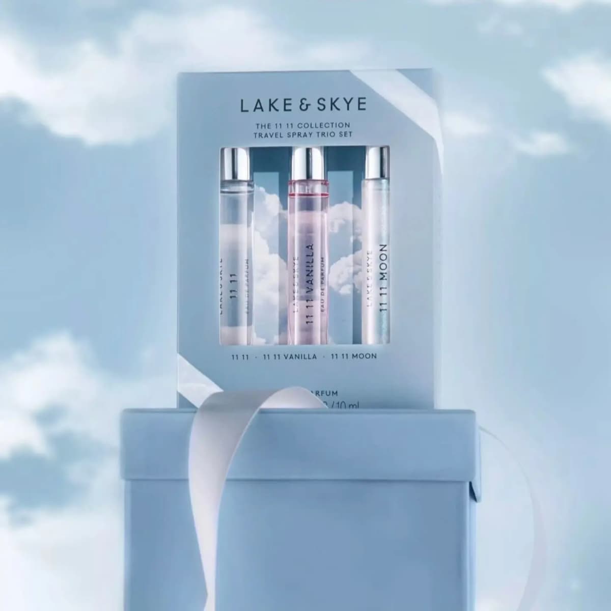 Lake & Skye 11 11 Collection trio set displayed atop a pale blue gift box with white ribbon and cloud-like background.