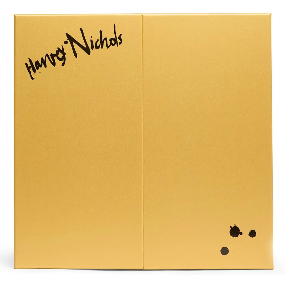Closed gold double-door box with black handwritten Harvey Nichols signature and ink splatter dots