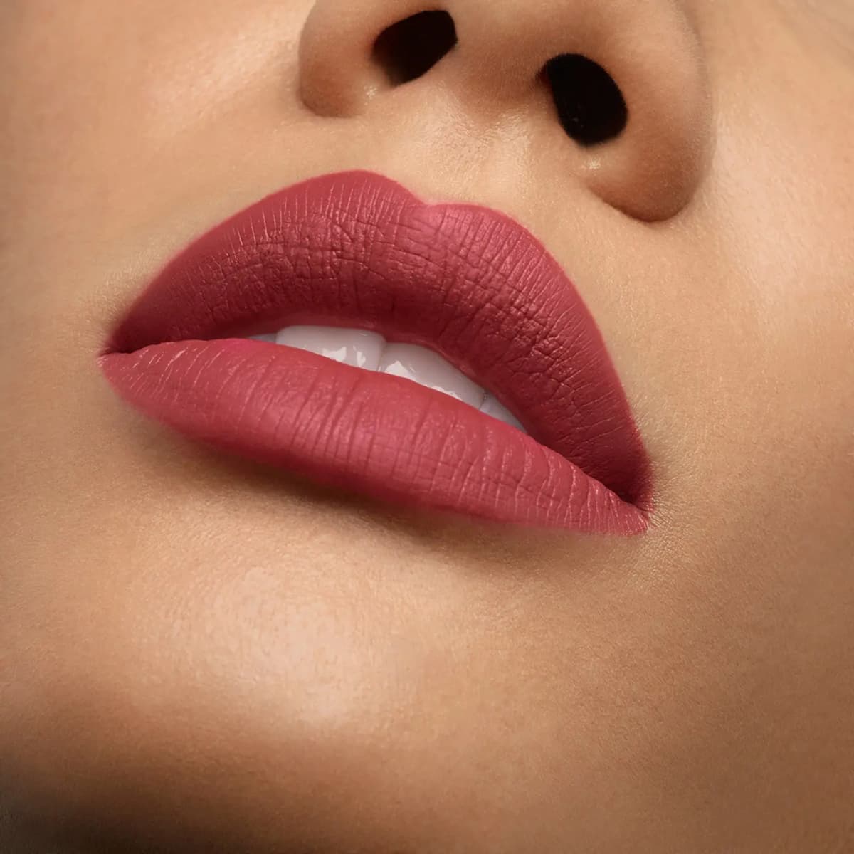 Slightly parted lips in a rosy red matte finish on medium skin