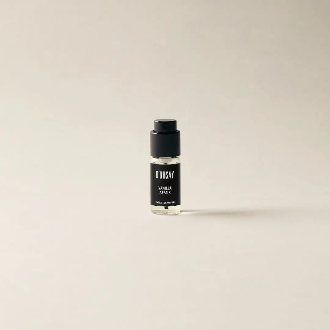Small clear D'ORSAY Vanilla Affair sample spray vial with black cap and black label on a cream background