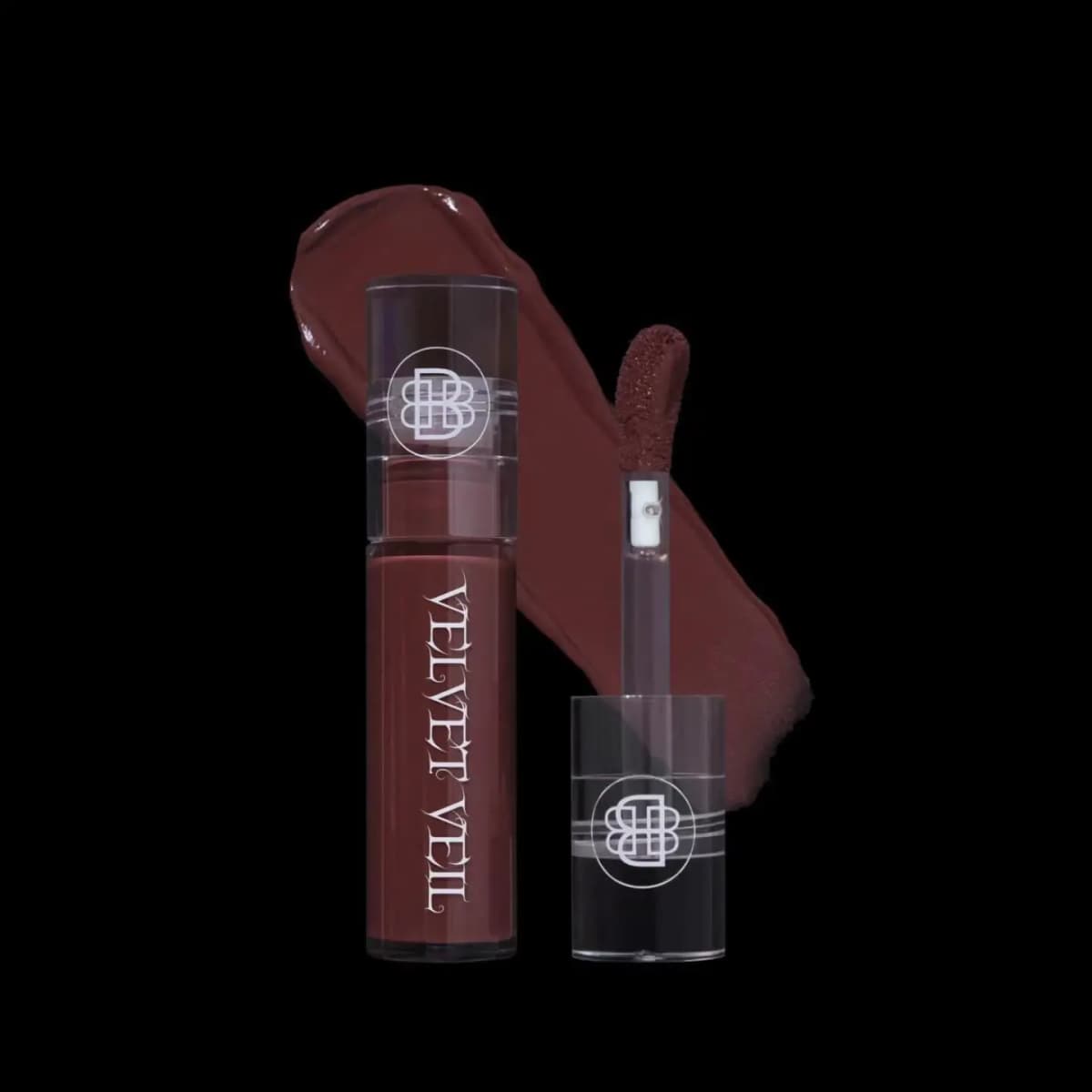 Muted burgundy-brown Velvet Veil lip mud tube with open doe-foot applicator and creamy swatch on black