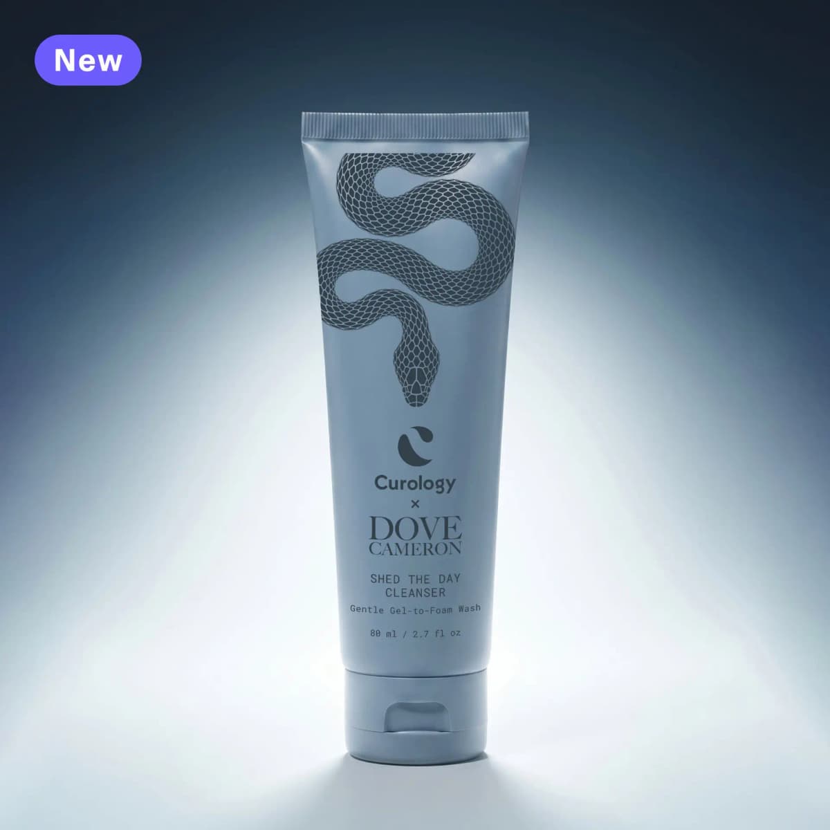 Slate blue Shed the Day Cleanser squeeze tube with a coiled dark snake illustration, lit from behind