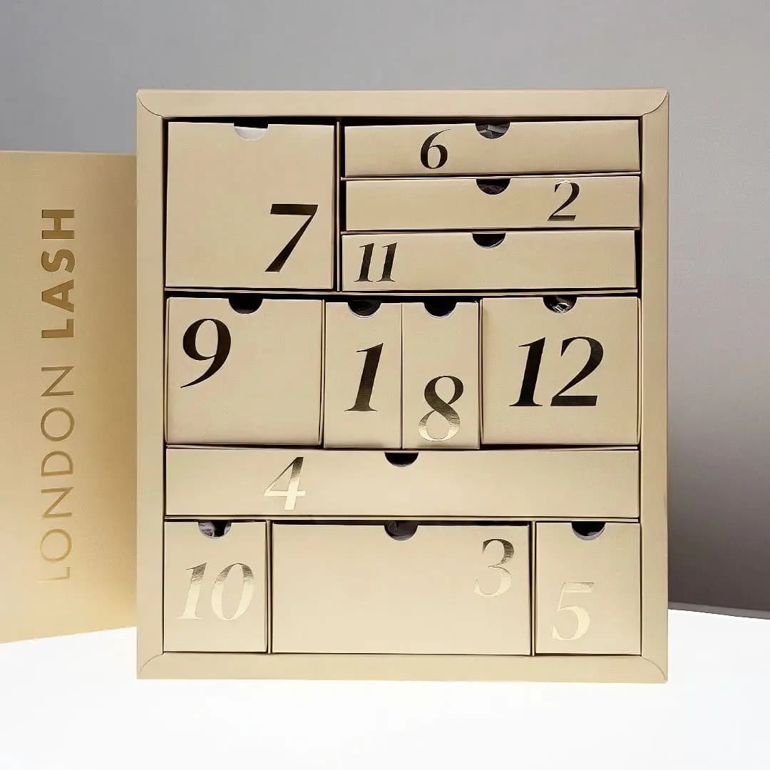 Closed beige London Lash Advent Calendar 2026 showing 12 numbered gold-foil drawers arranged in a grid