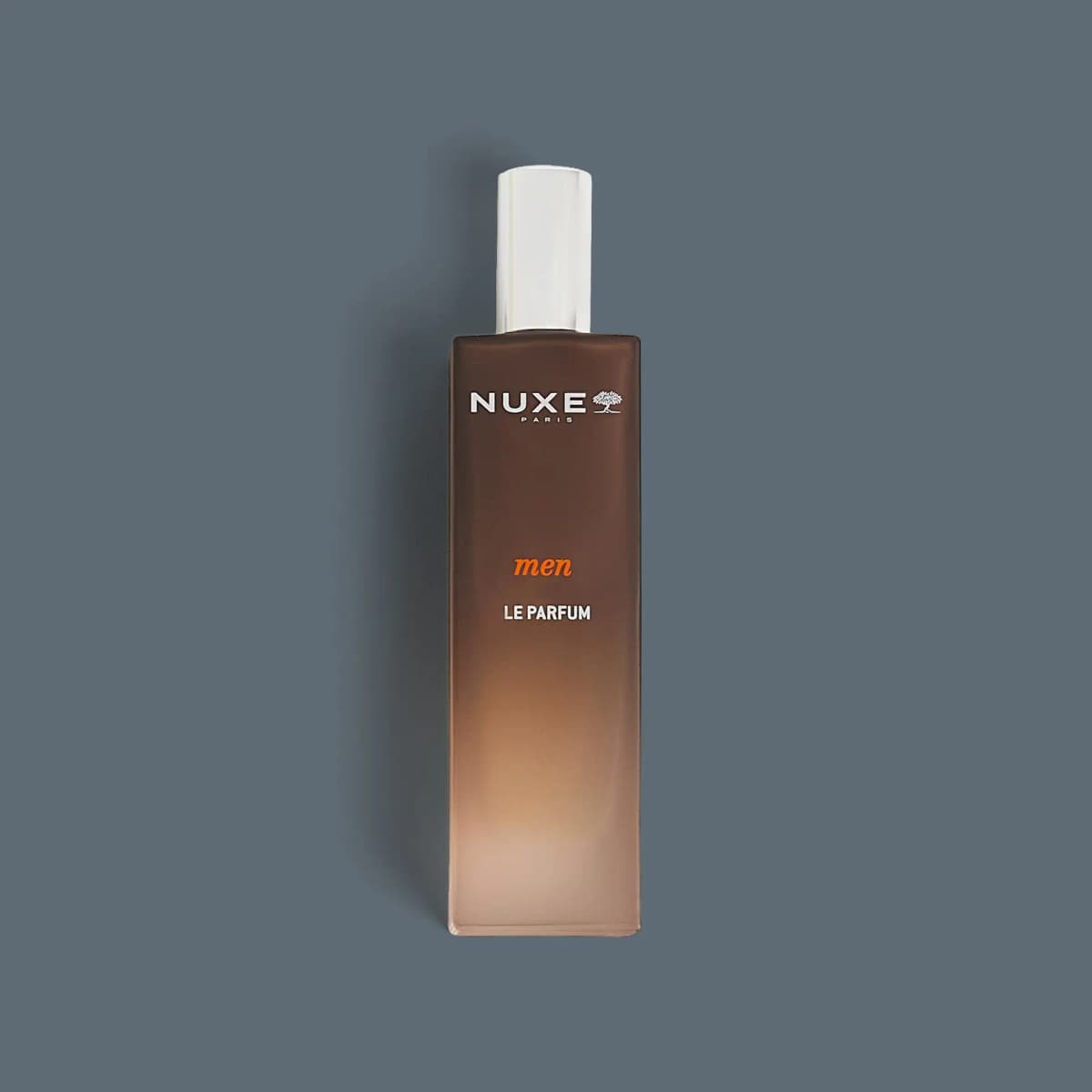 NUXE men Le Parfum in a tall frosted brown-to-beige gradient bottle with a silver cap on a slate background