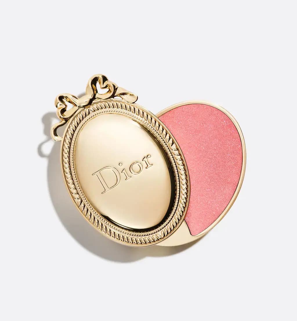 Dior Médaillon lip balm in a gold oval medallion case with a bow, opened to show sparkling pink balm