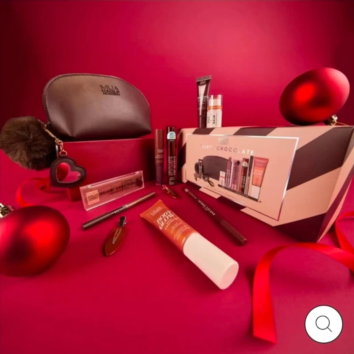 MUA Velvet Chocolate gift box with brown makeup bag, pompom keyring, eyeshadow palette, Body Glow and liners on red.