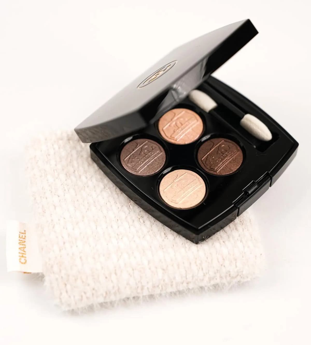 Chanel Holiday 2026 embossed four-shade eyeshadow quad open on a tweed pouch
