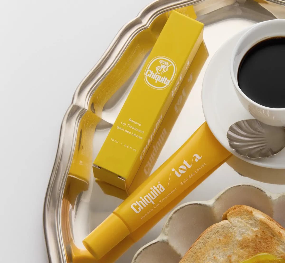 Yellow box and tube on a silver tray beside an espresso cup and toasted bread