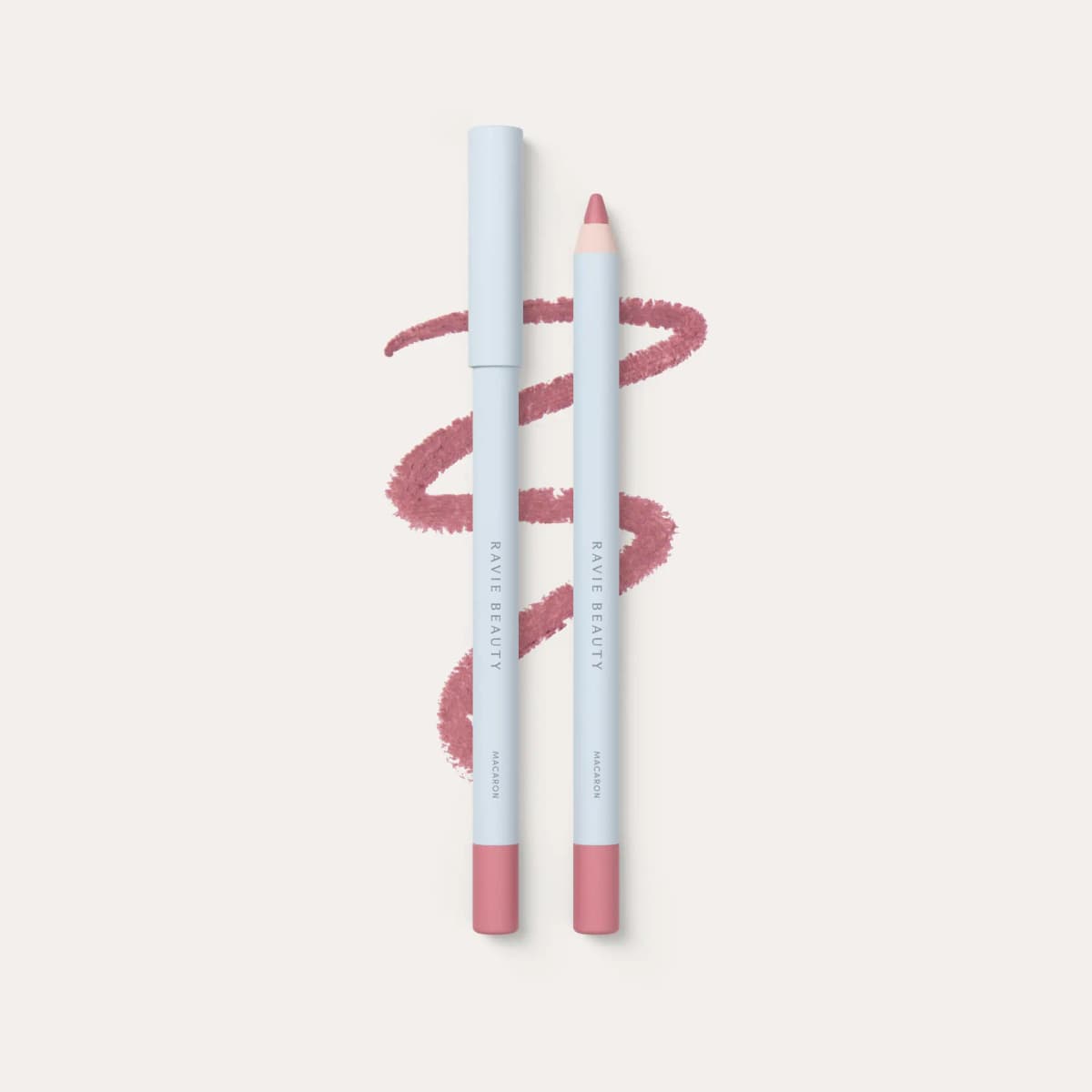 Ravie Beauty lip liner in Macaron, capped and uncapped pencils beside a soft pink scribble swatch.