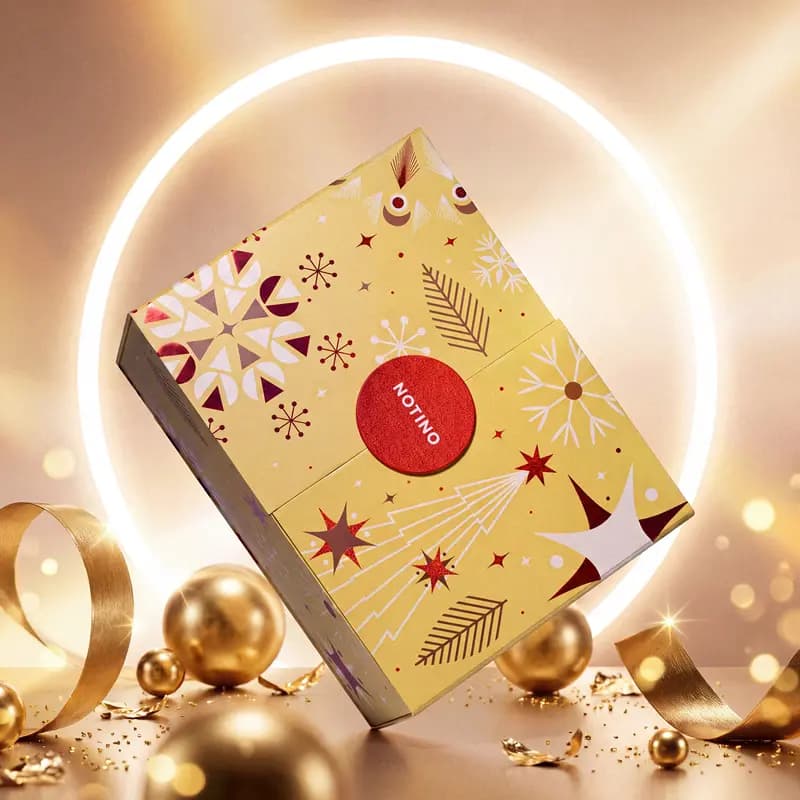 Gold Notino Exclusive advent calendar box with red and white star pattern displayed inside a lit ring with gold baubles