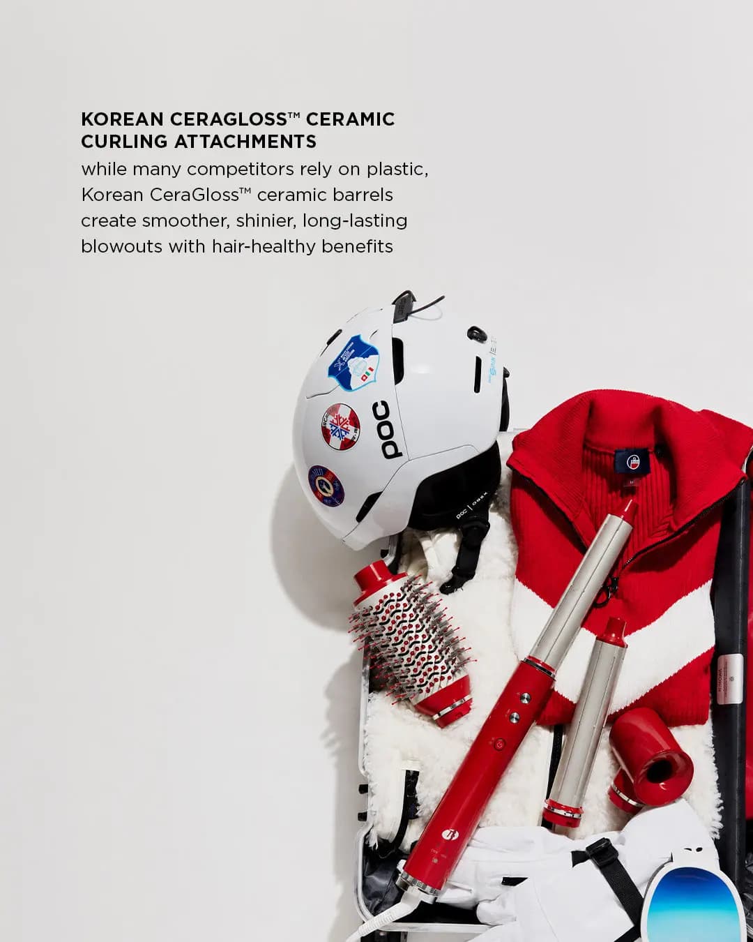 Styler, barrels, brush and concentrator packed in a suitcase with a ski helmet and red sweater, captioned CeraGloss barrels