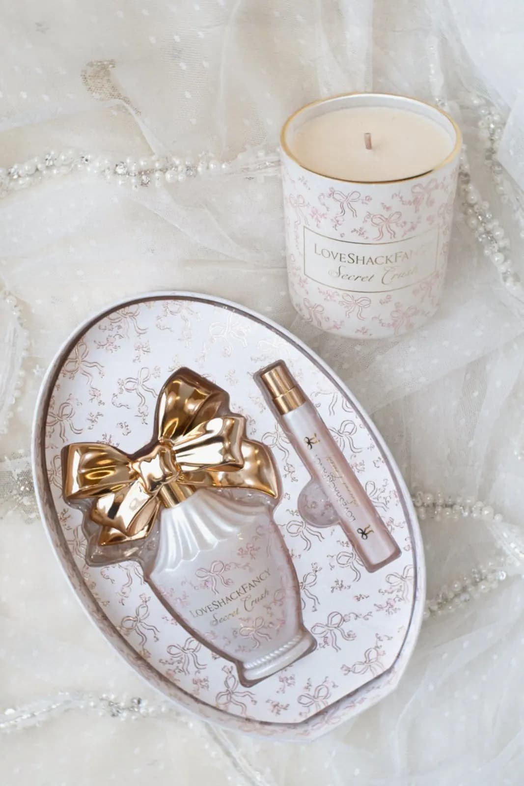Open Secret Crush Vanity Set box with gold-bow bottle and travel spray next to the Secret Crush candle on beaded tulle