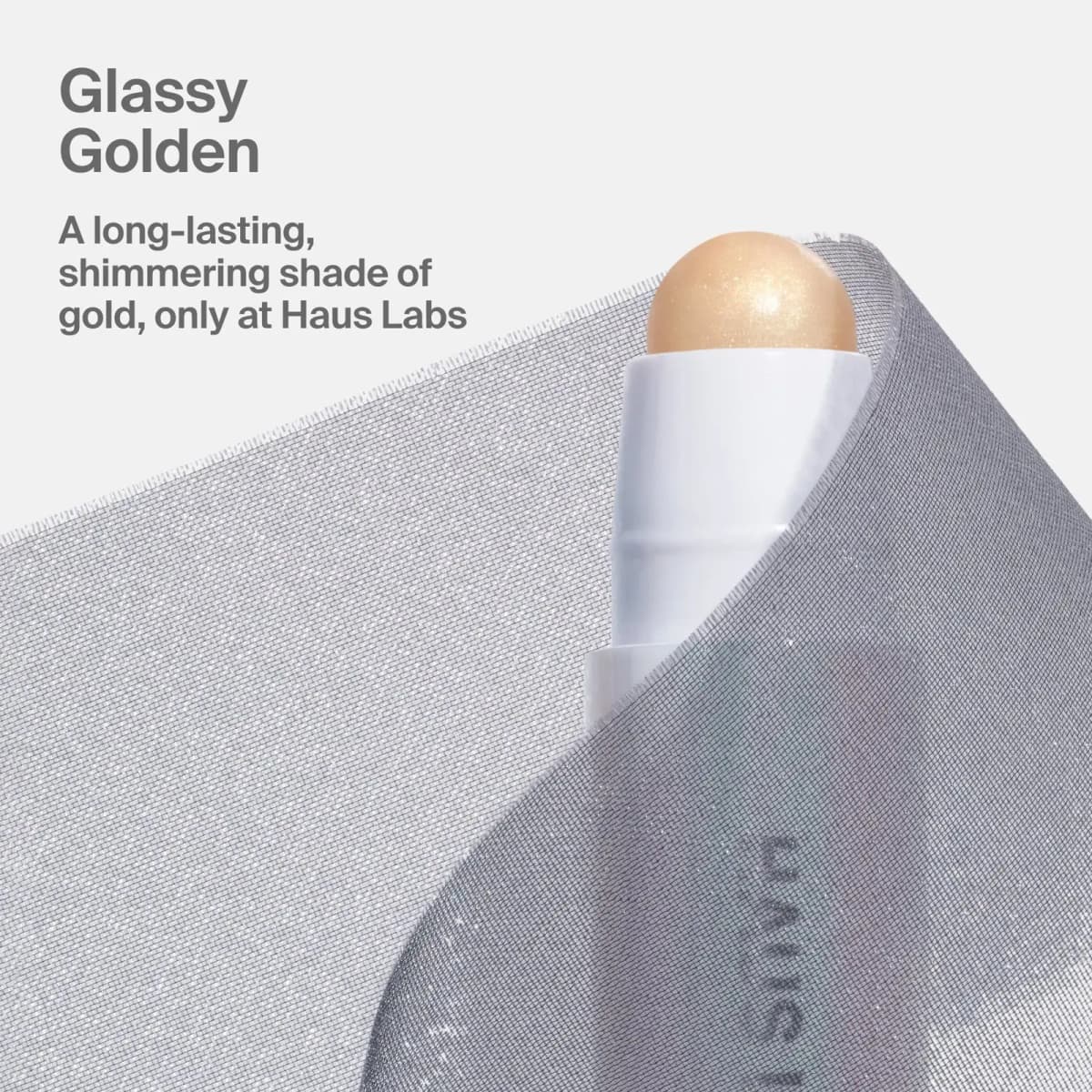 Pale gold shimmering balm tip peeking from sheer silver mesh fabric beside "Glassy Golden" text