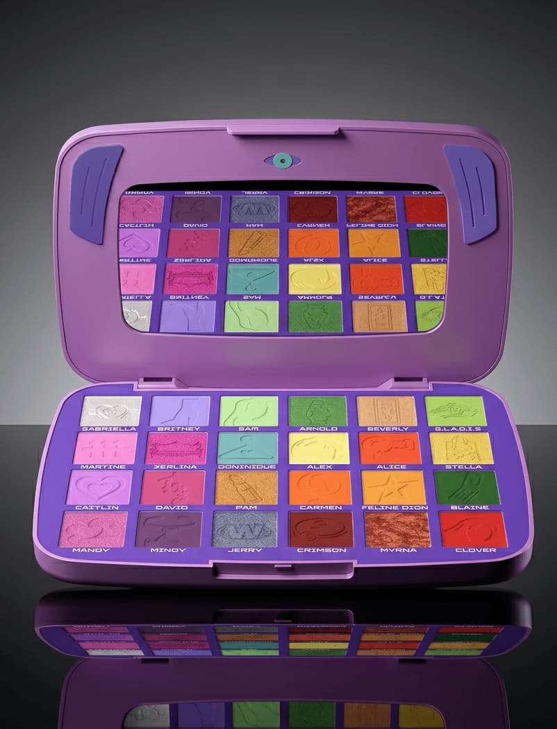 Open purple laptop-style eyeshadow palette with 24 named shades reflected in mirror lid on dark background.