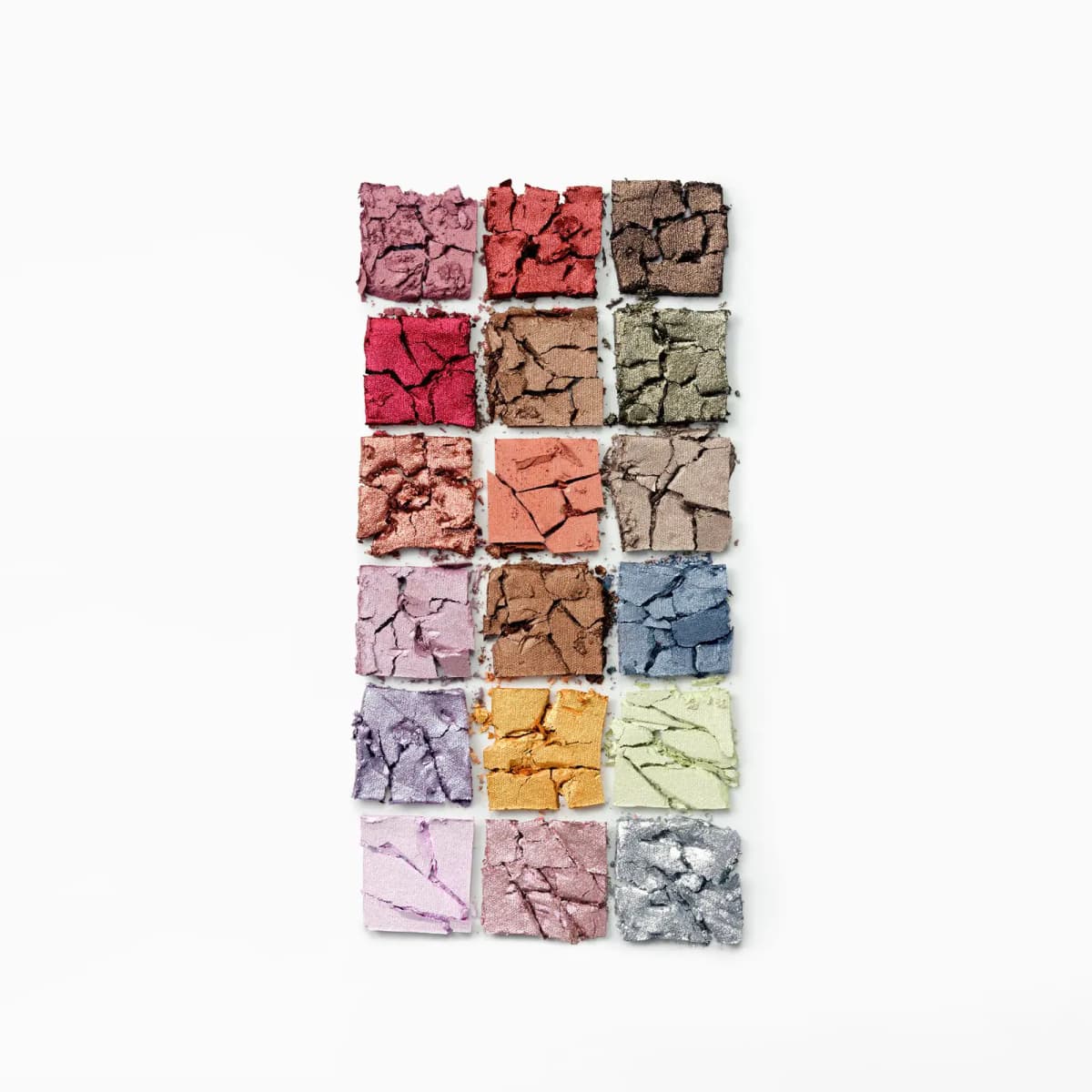 Crushed eyeshadow pans arranged in a grid, showing cracked textures of each shimmer and matte shade