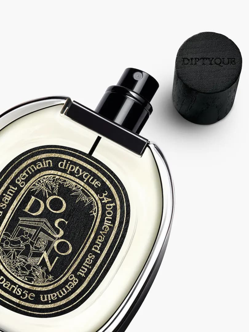 Close-up of uncapped Do Son spray nozzle next to black wooden cap embossed Diptyque