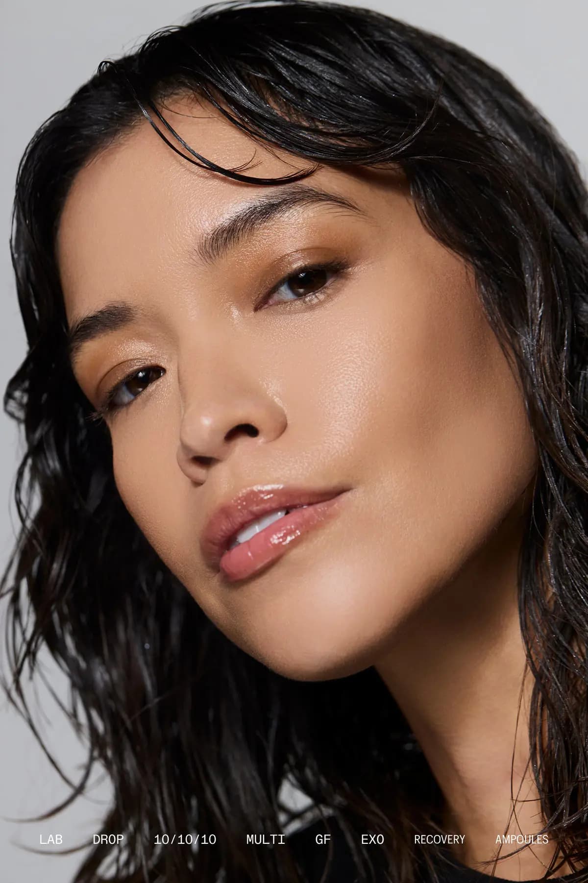 Dark-haired model with wet waves and dewy glowing skin, captioned Lab Drop 10/10/10 Multi GF Exo Recovery Ampoules