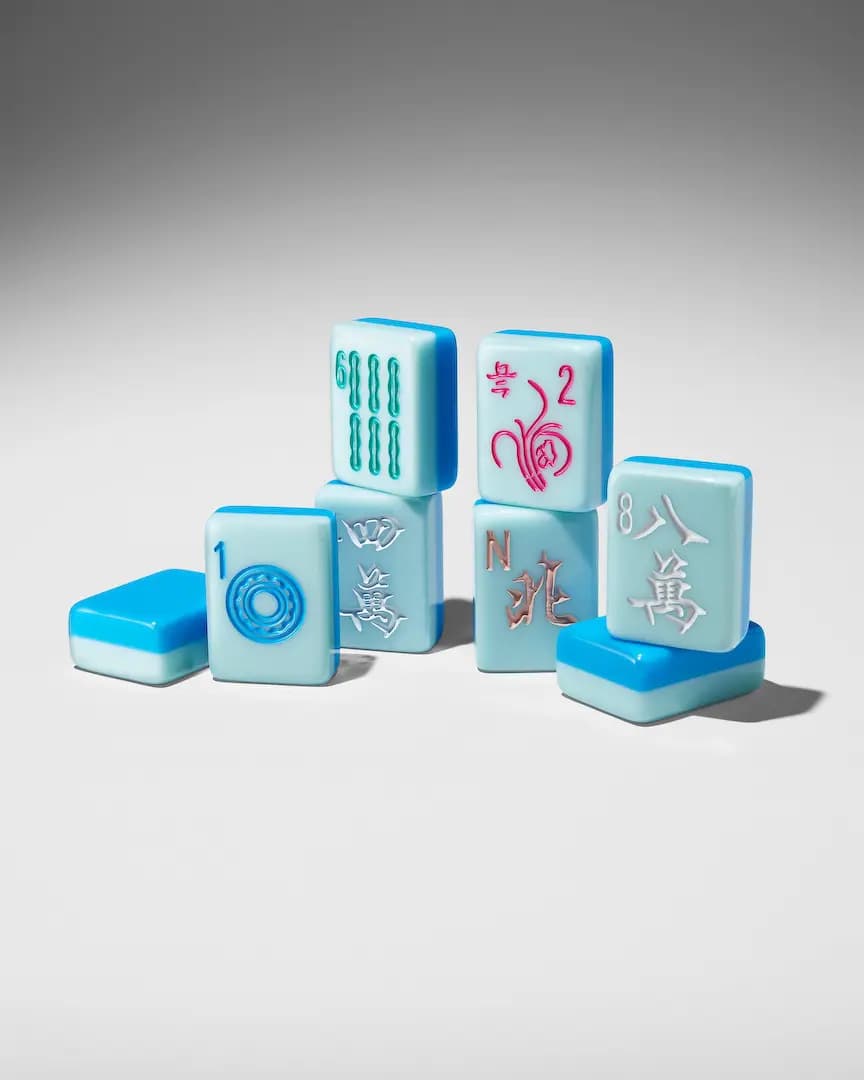 Stacked aqua mahjong tiles with bright blue backs, showing a 1 dot, 6 bamboo, flower, North wind and 8 character tile