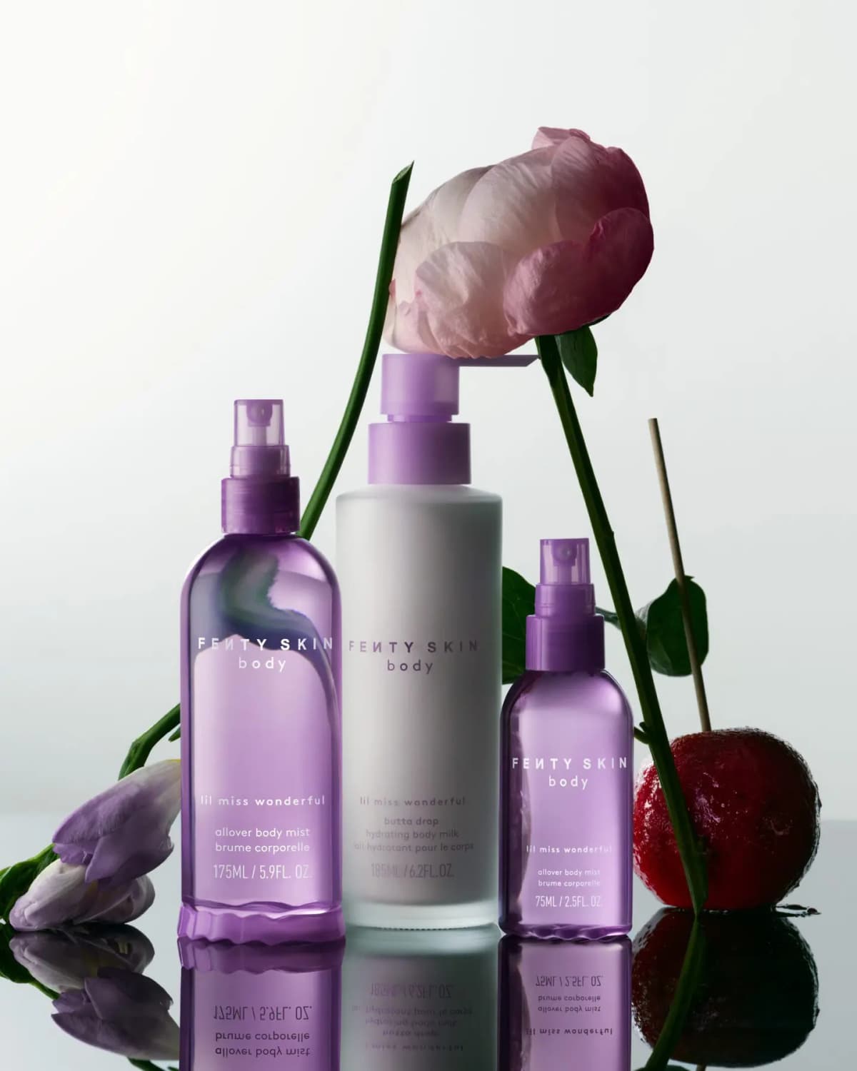 Three Fenty Skin Lil Miss Wonderful body products in purple and frosted white bottles surrounded by peony, freesia, and a