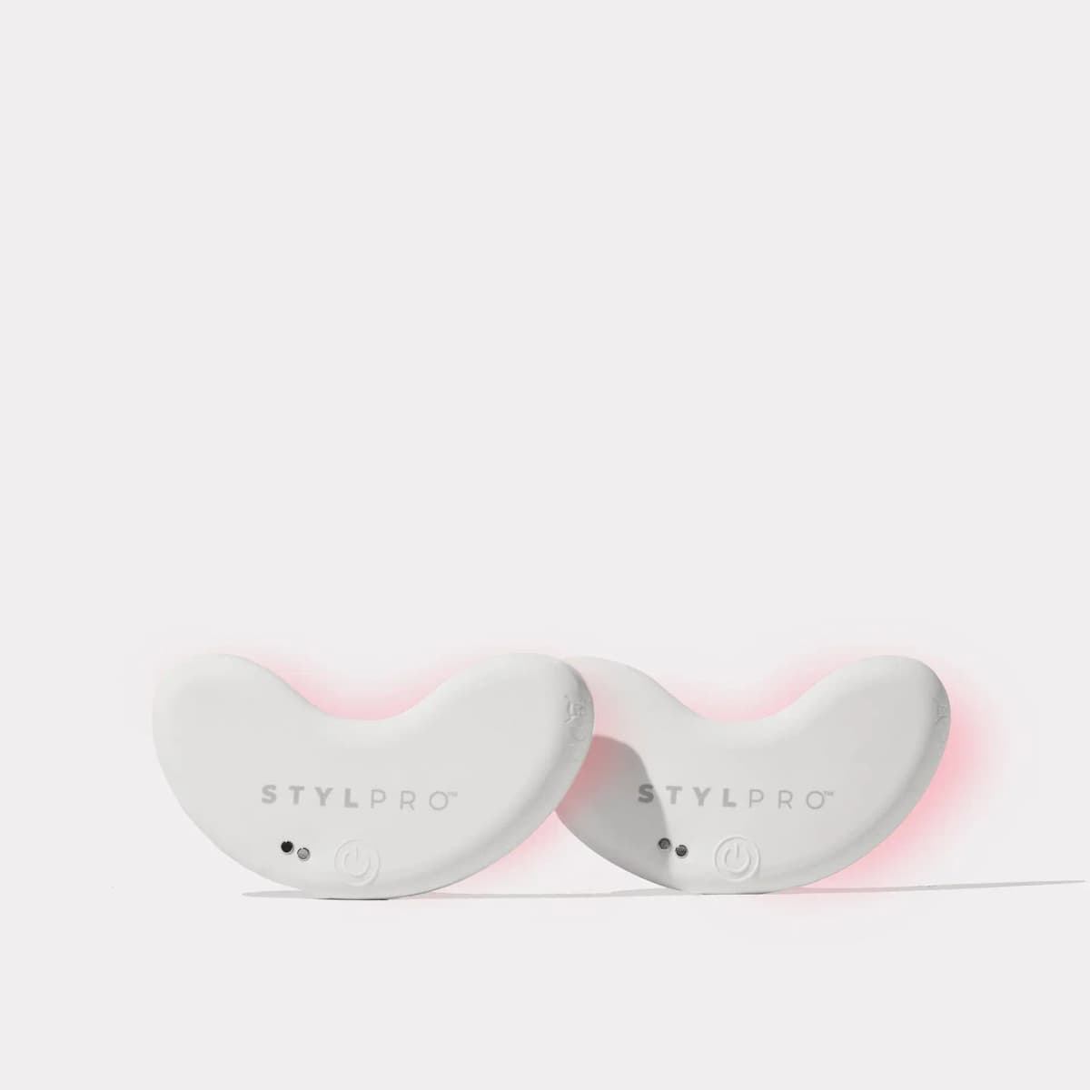 Two white kidney-shaped STYLPRO Red LED Patch Duo pads standing upright with a soft pink glow on a white background
