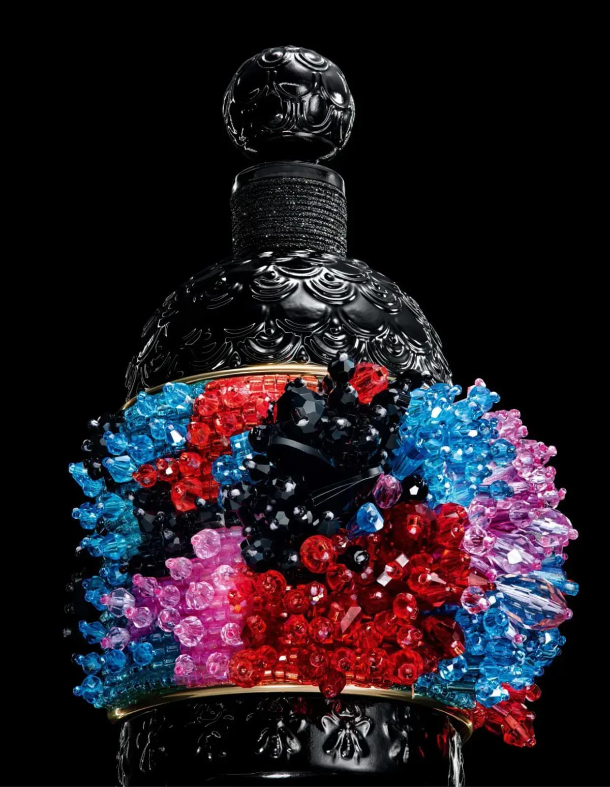 Close-up of faceted red, blue, pink and black crystal beads clustered on the cuff around the black bottle