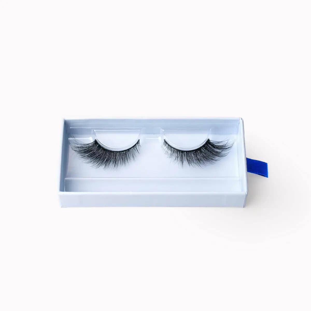Overhead view of a bold, dramatic voluminous strip lash pair inside a white tray with blue tab.