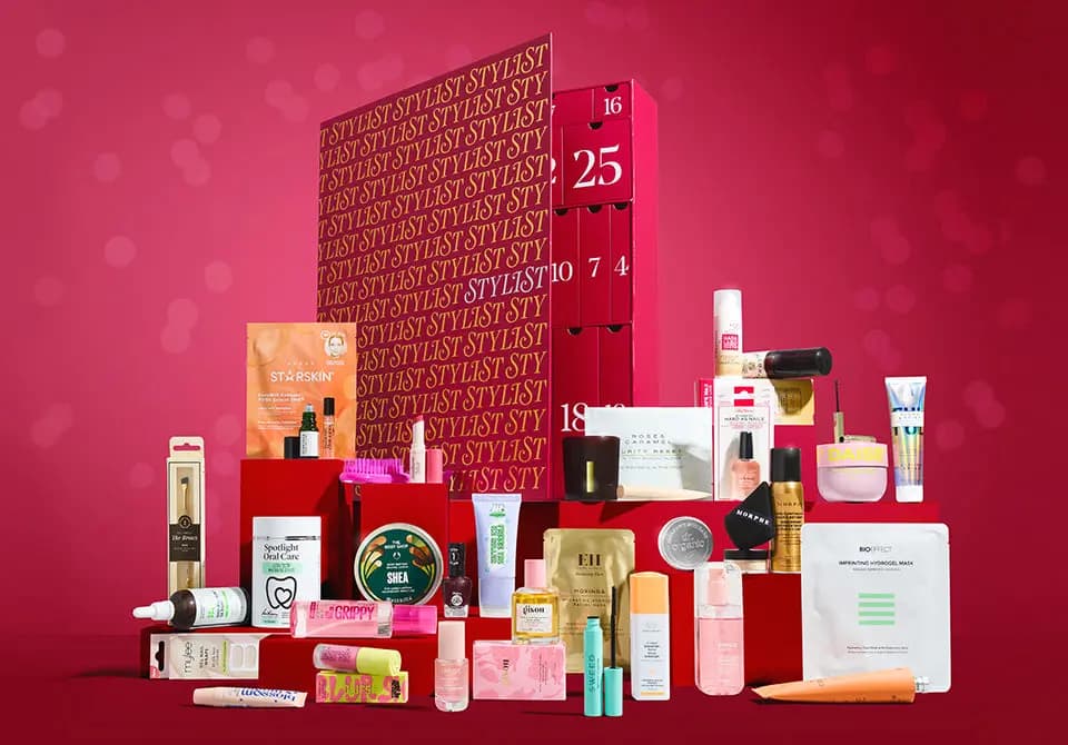 Open red STYLIST advent calendar with numbered doors, surrounded by its beauty products on red plinths