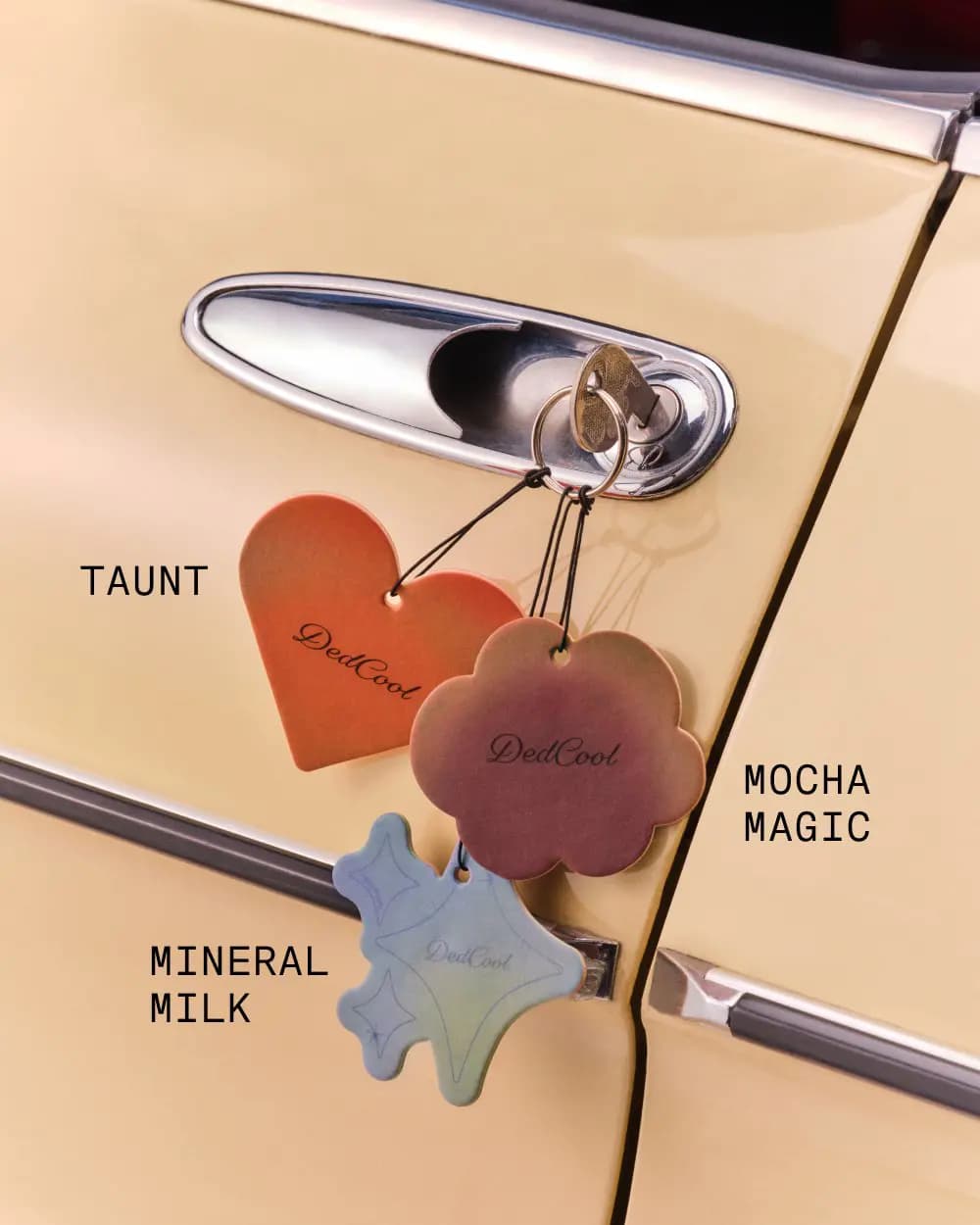 Taunt, Mocha Magic and Mineral Milk air fresheners hanging from keys in a cream car door lock