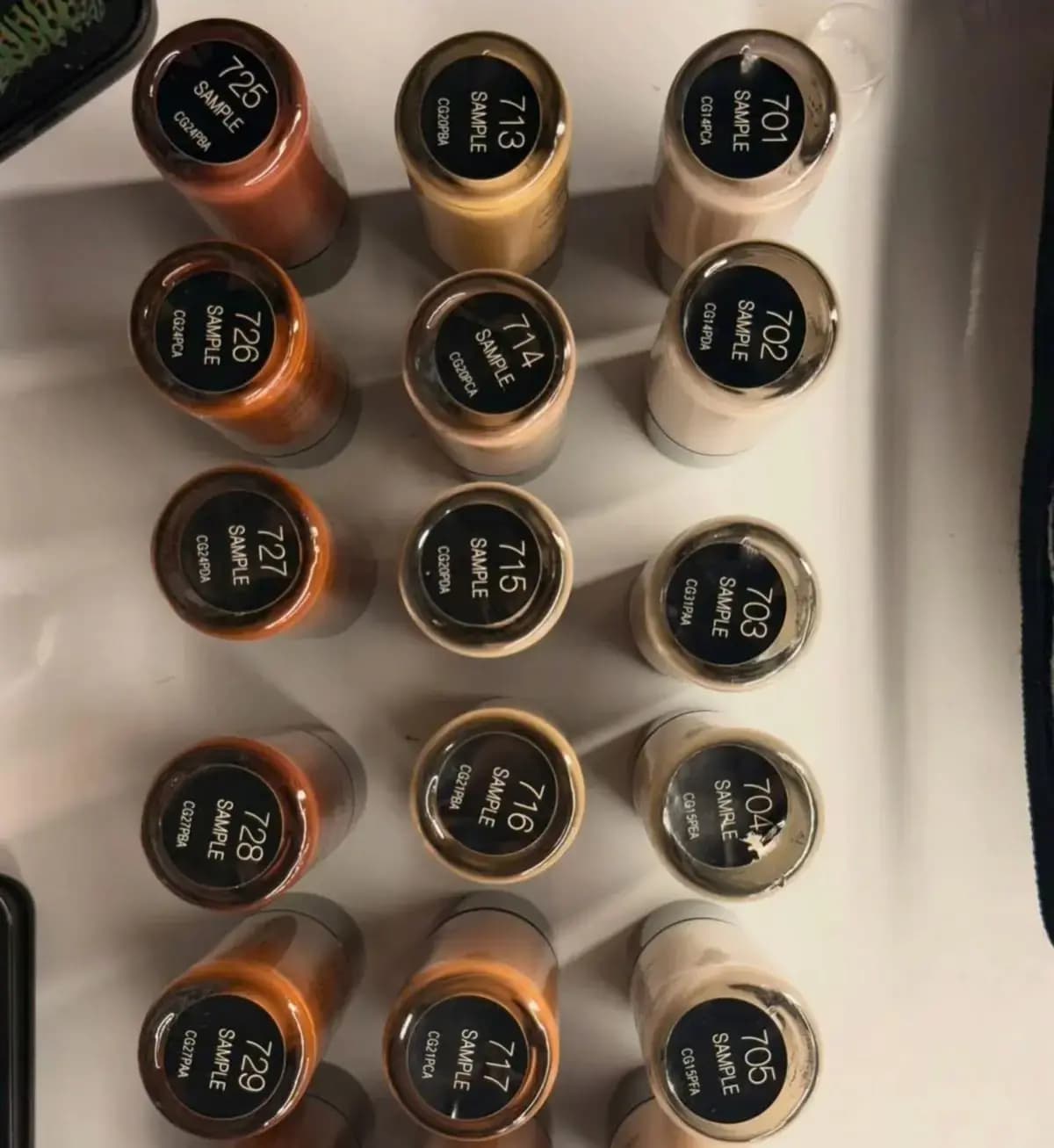 Top-down view of sample bottles with black caps numbered 701 to 729 in light to orange-tan shades