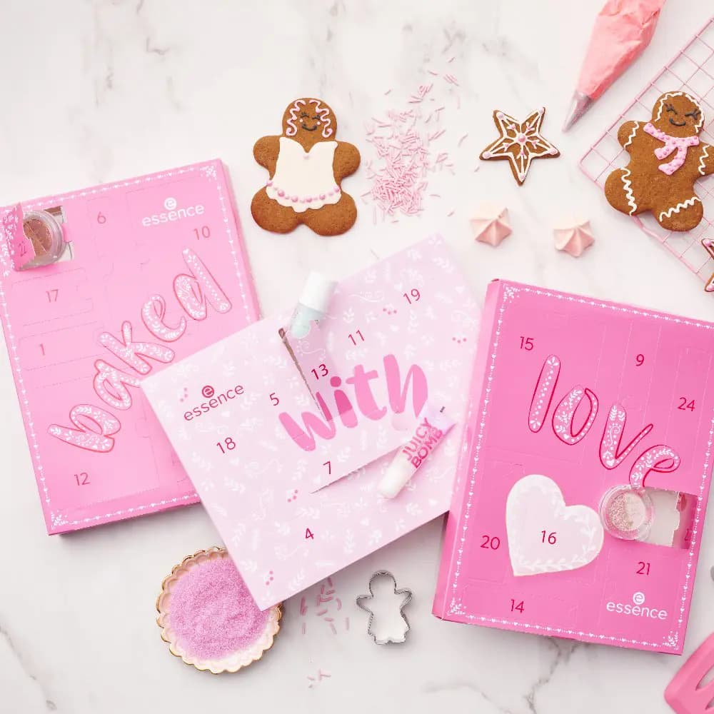 Three pink calendar panels spelling baked, with, love among gingerbread cookies, sprinkles and meringues on marble
