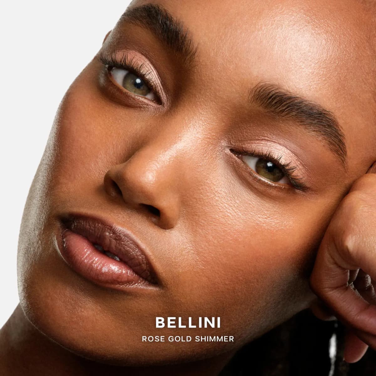 Close-up of a model with deep skin wearing soft Bellini rose gold shimmer on the lids, glossy nude lips