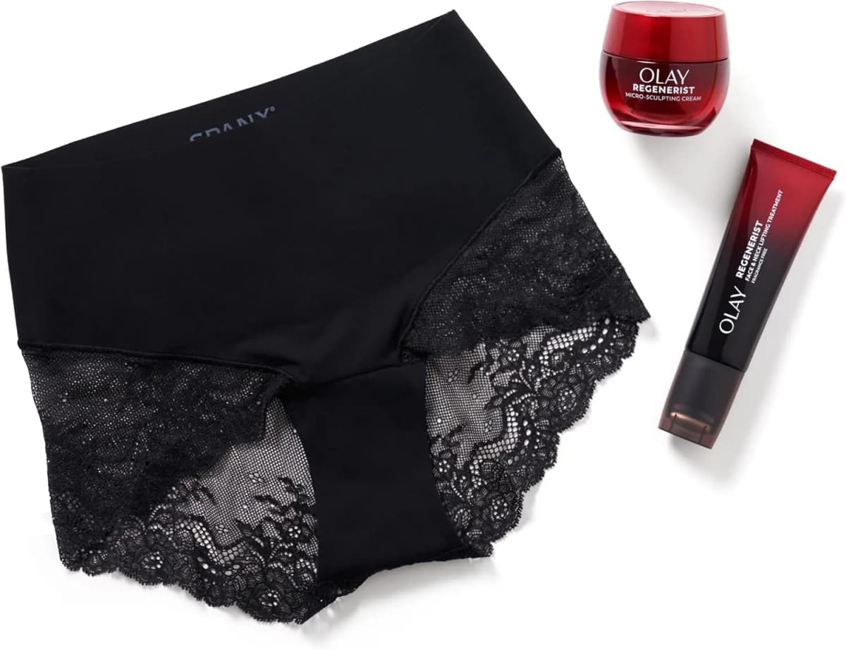 Black Spanx lace hi-hipster laid flat beside a red OLAY Regenerist cream jar and Face & Neck Lifting Treatment tube