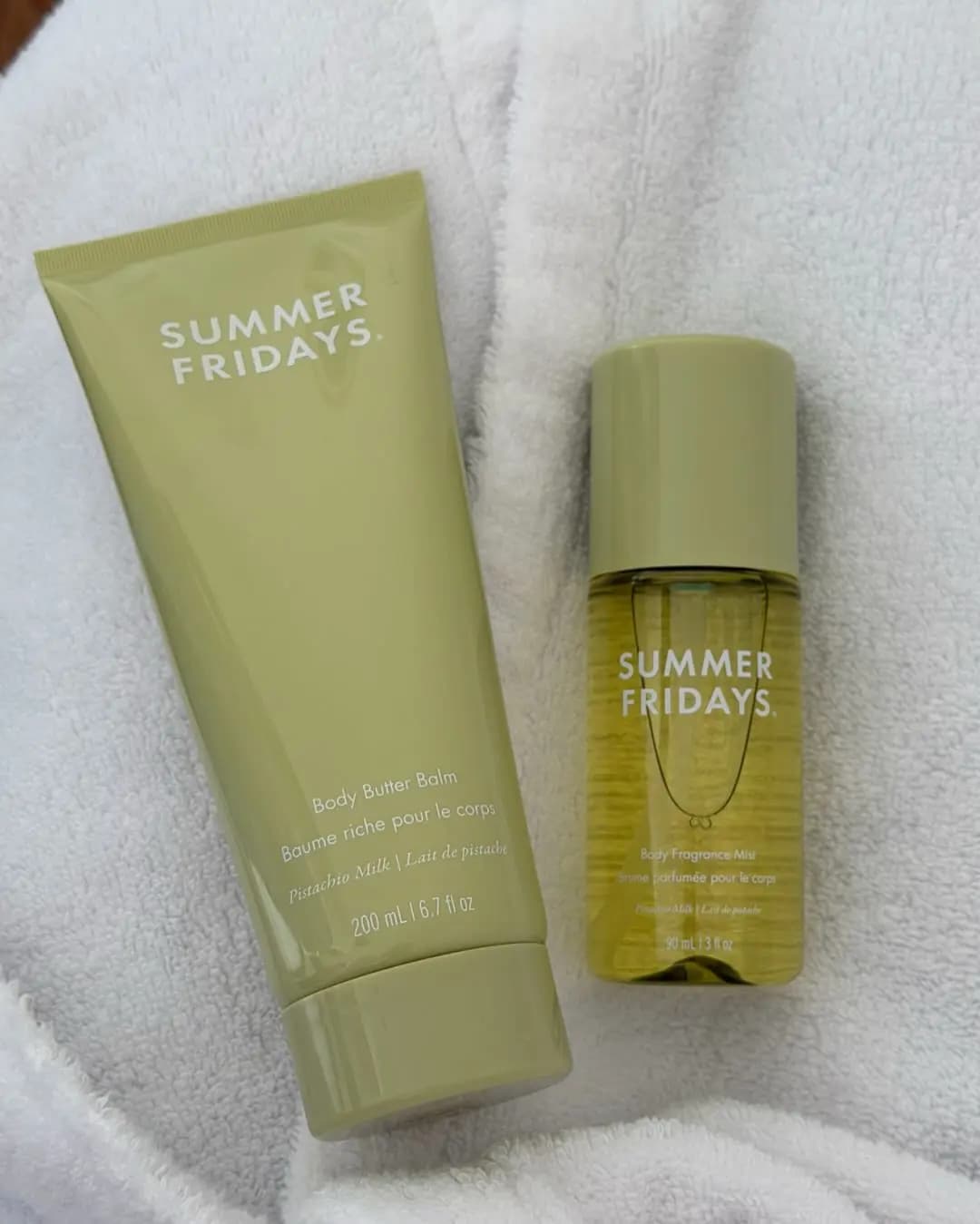 Summer Fridays Pistachio Milk Body Butter Balm tube and Body Fragrance Mist in sage green lying on a white towel.