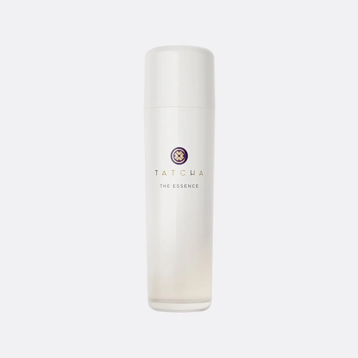Tatcha The Essence in a tall pearly white bottle with purple and gold logo on a light grey background