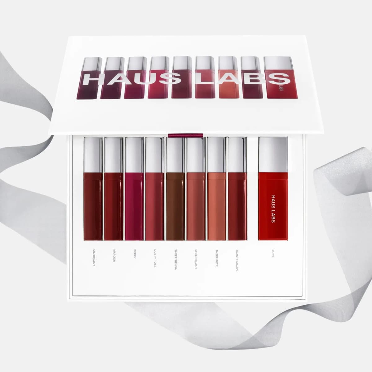 Open vault showing nine lacquers labelled Mahogany to Ruby in a white tray, with a sheer grey ribbon behind