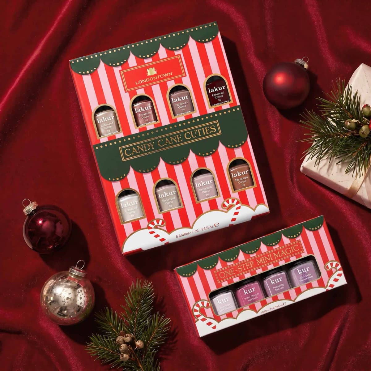 LONDONTOWN Candy Cane Cuties and One-Step Mini Magic boxes on red velvet with baubles, pine sprigs and a wrapped gift