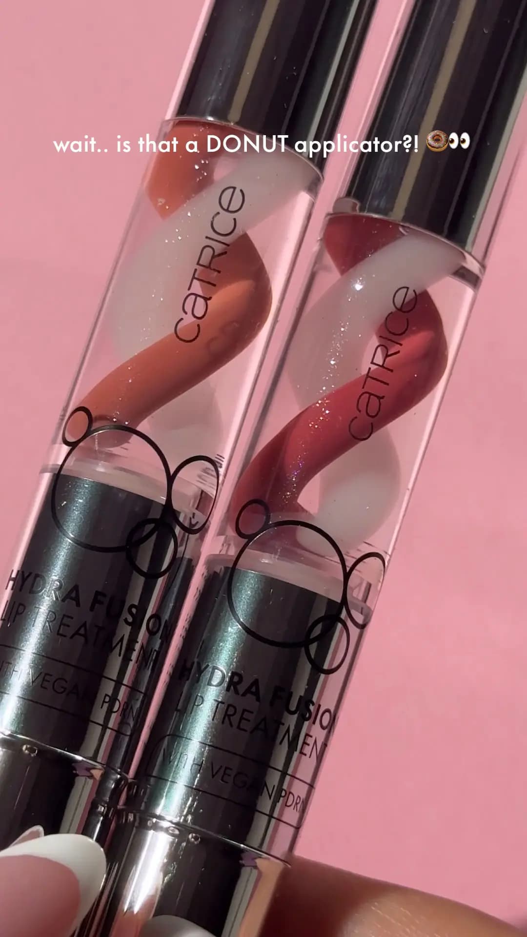 Two Catrice Hydra Fusion Lip Treatment tubes held against pink, showing nude and rose swirled formulas with white
