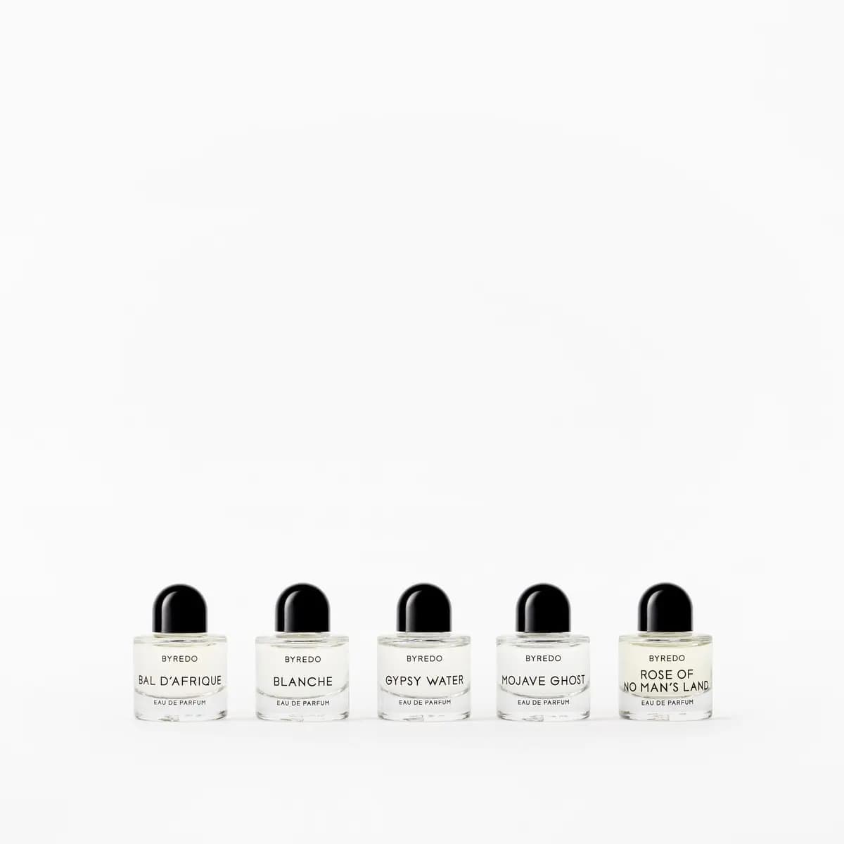Five clear Byredo minis lined up low on a white backdrop, Gypsy Water placed before Mojave Ghost