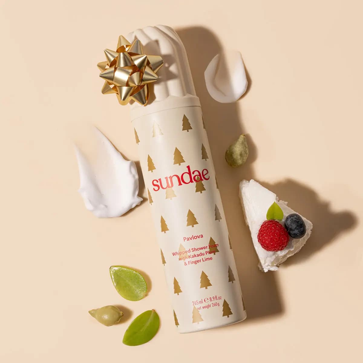 Cream Pavlova can with gold tree print and gold bow beside pavlova slice with berries and foam swatches